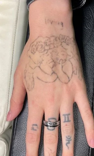 Before: line drawing tattoo across the back of the hand