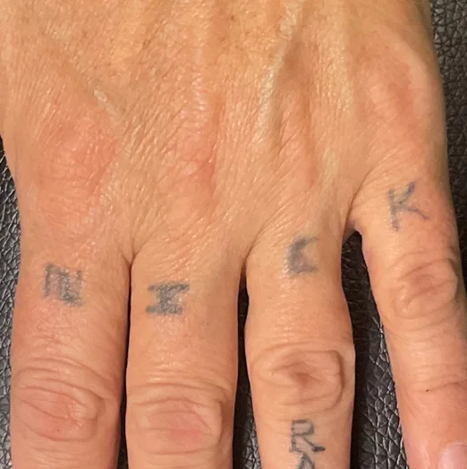 Before: lettering tattooed across four knuckles